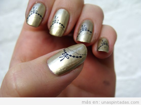 Diseño de uñas con color dorado metálico y dibujos lazos