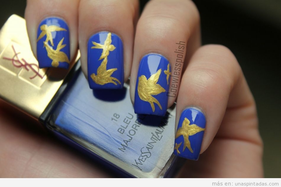 Decoración de uñas con dibujo de pájaro dorado sobre fondo azul